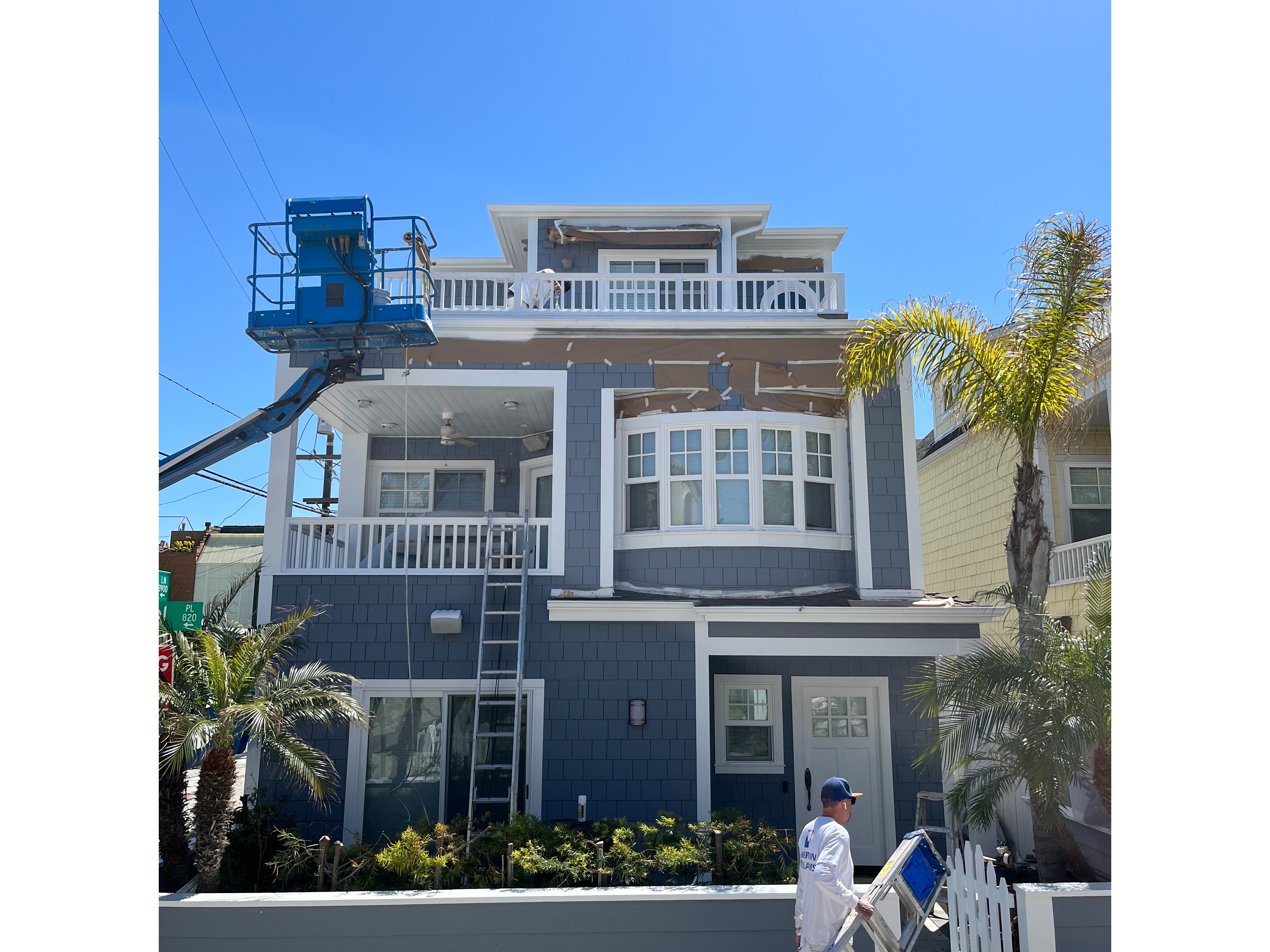 A Man Paints a House Under a Bright Sun