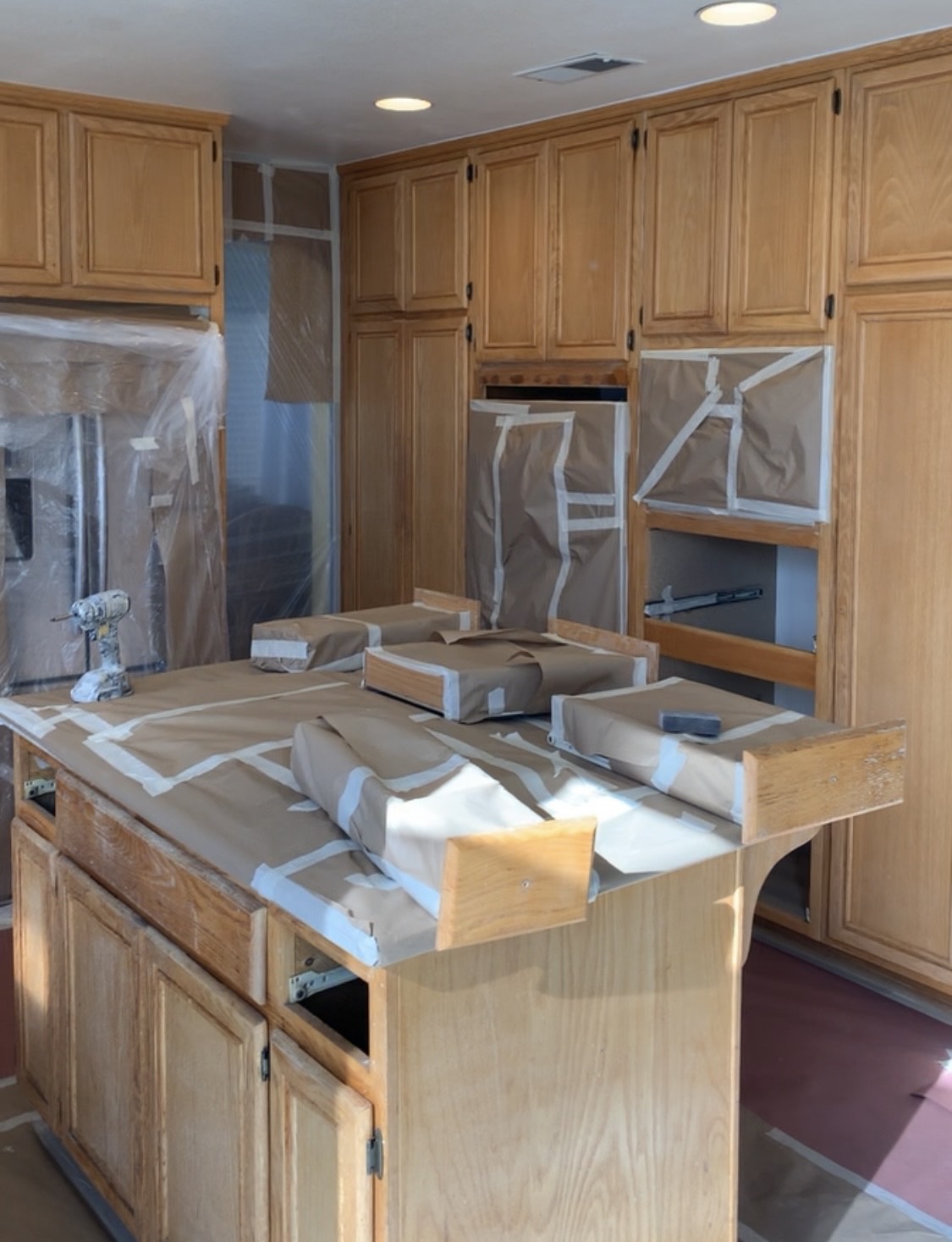 A Kitchen Scene Showing Cabinets and Countertops Wrapped in Plastic