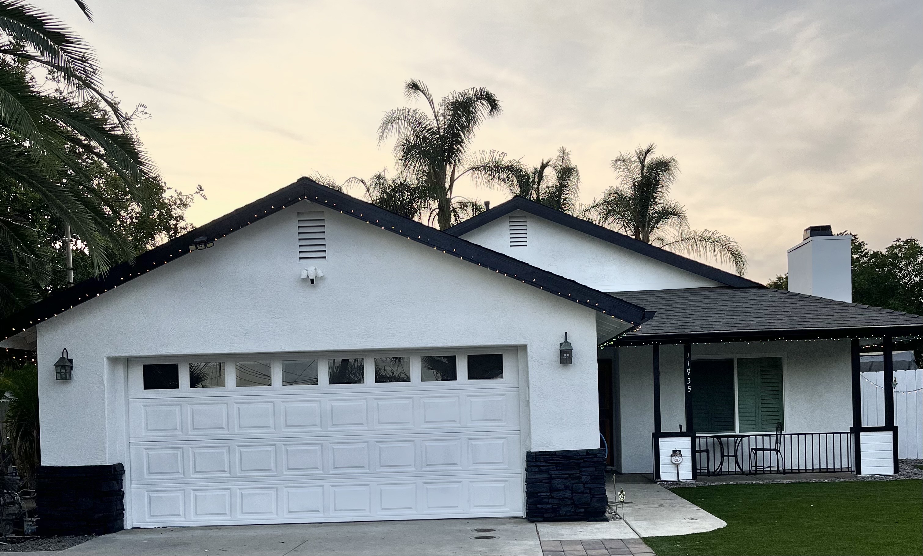 A White House With a Garage Surrounded by Tall Palm Trees